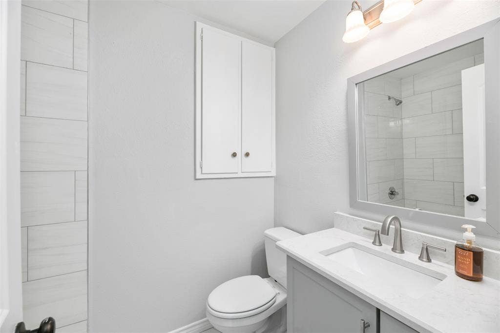 White vanity with stone-finish countertop, integrated sink, and brushed nickel fixtures