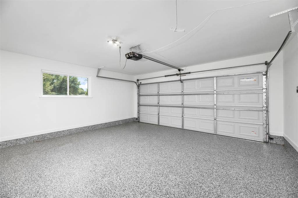 Attached two-car garage with an automatic door opener, light-colored epoxy flooring, and a window