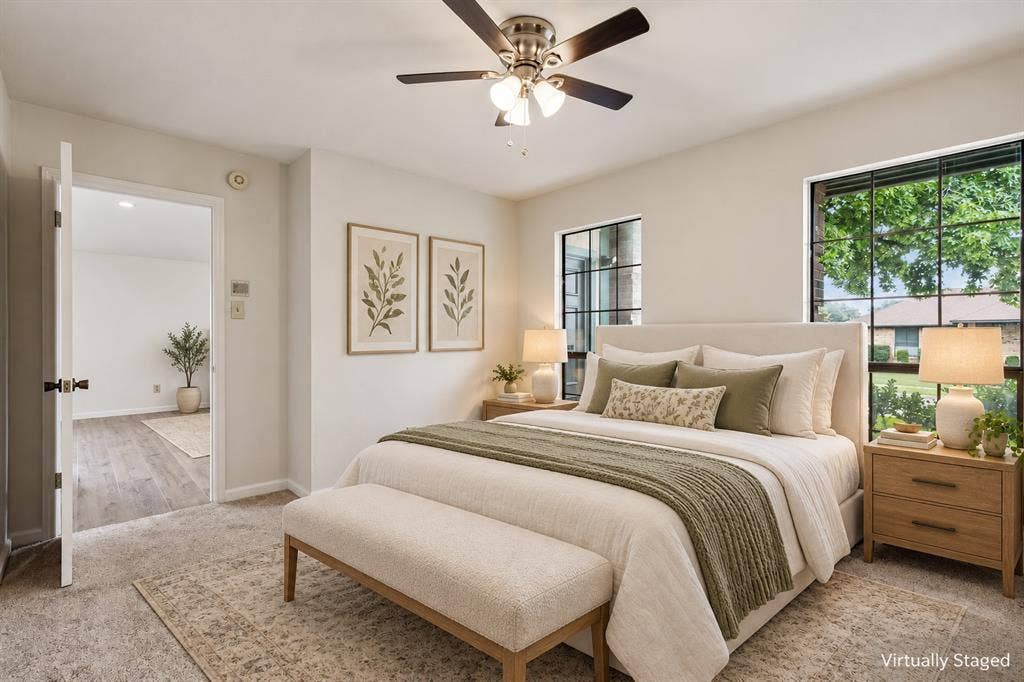 Carpeted flooring, ceiling fan with integrated lighting, and two large windows with black frames