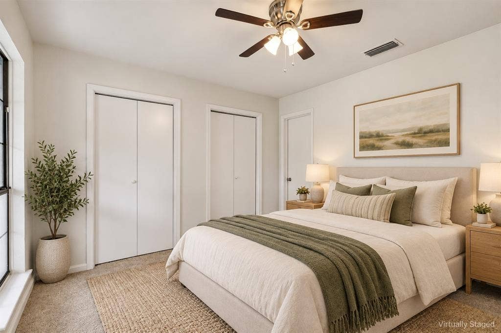 Carpeted flooring, ceiling fan with light fixture, multiple windows, and two closet entries