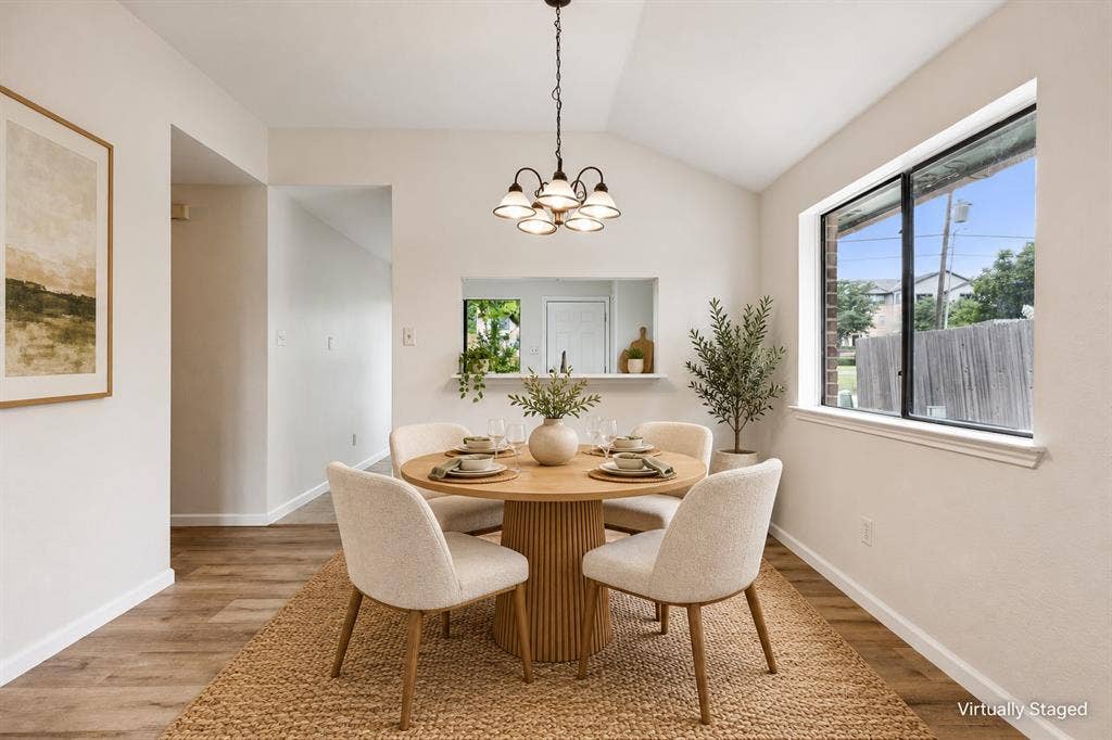 Vaulted ceiling, wood-finish flooring, recessed pass-through window, and a modern chandelier