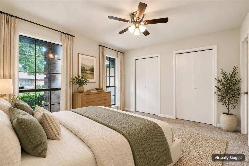 Carpeted flooring, two paneled bi-fold closet doors, ceiling fan with light kit, and large windows with black frames