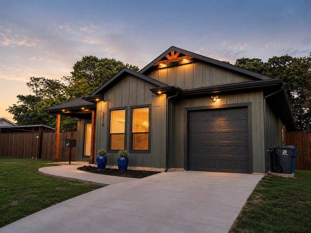 3210 Carpenter Avenue, Dallas, TX 75215 Board and batten exterior with contrasting trim, attached garage, concrete driveway, covered entry, and wood privacy fencing
