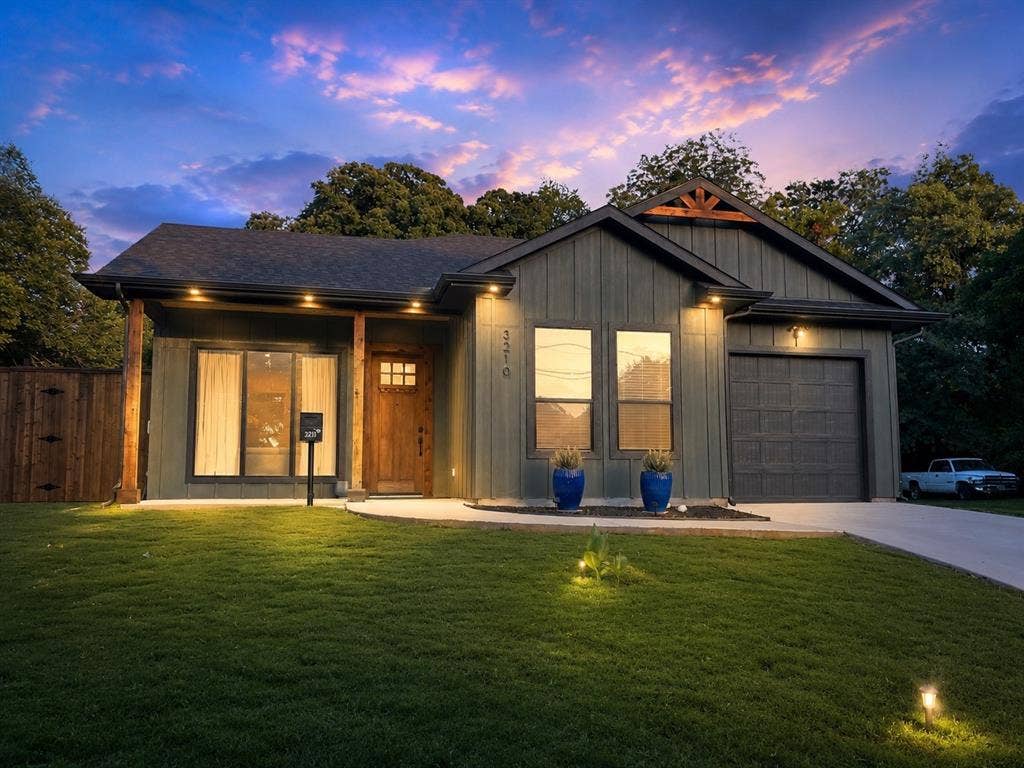 3210 Carpenter Avenue, Dallas, TX 75215 Contemporary exterior with board and batten siding, a dark asphalt shingle roof, wood-finish columns, a wood-finish front door, and an attached garage with a dark panel door
