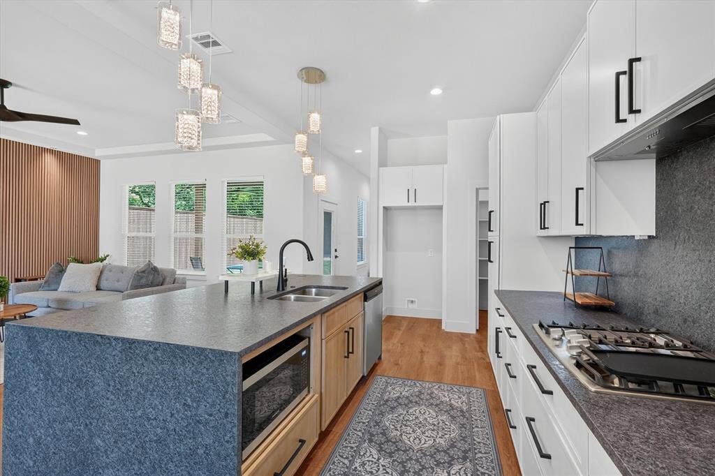 3210 Carpenter Avenue, Dallas, TX 75215 Spacious kitchen featuring an expansive island with an undermount sink, gas range, built-in microwave, and wood-finish flooring