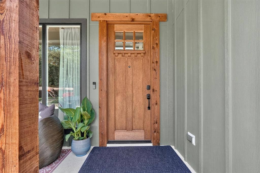 3210 Carpenter Avenue, Dallas, TX 75215 Craftsman-style wood entry door with glass paneling, board and batten siding, and a prominent wood structural beam