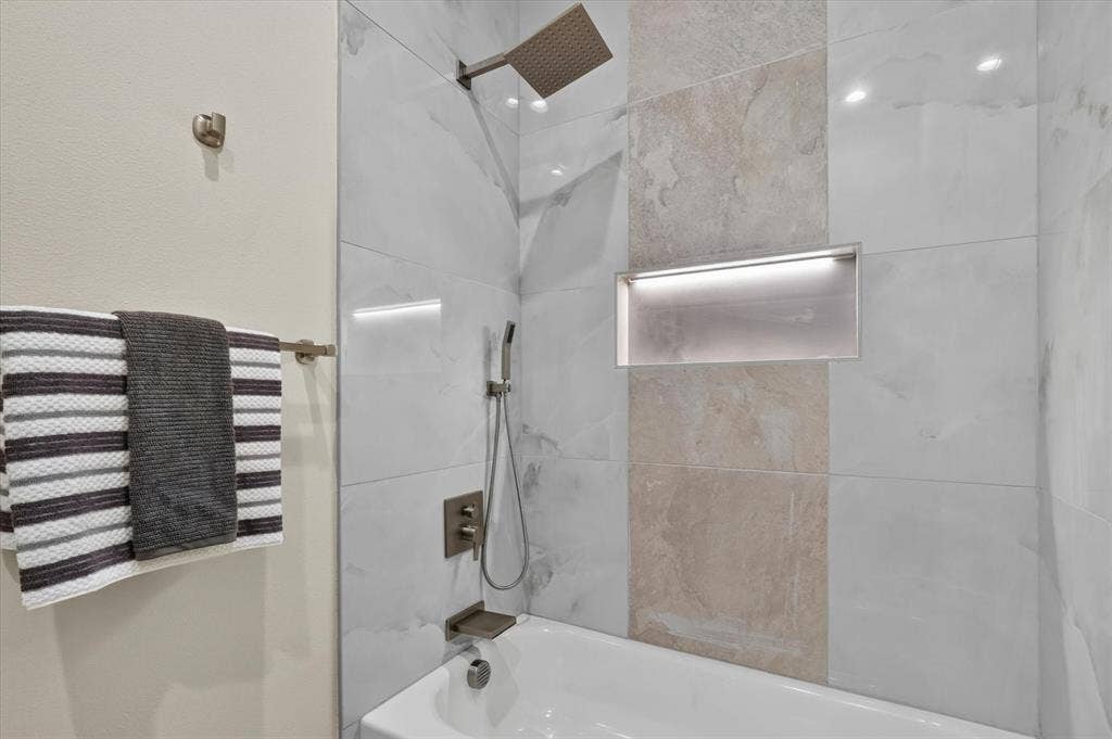3210 Carpenter Avenue, Dallas, TX 75215 Bathtub with mixed tile surround, integrated shower niche with accent lighting, and a rain shower head with a handheld sprayer