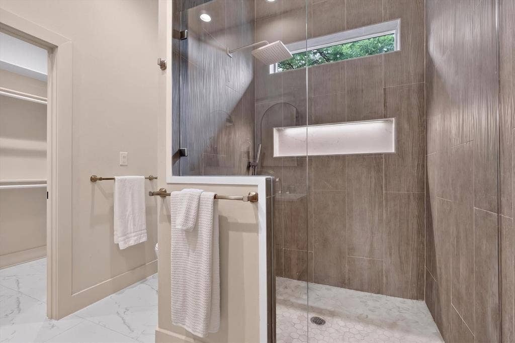 3210 Carpenter Avenue, Dallas, TX 75215 Glass-enclosed shower with a rainfall showerhead, tiled walls, and an illuminated recessed niche