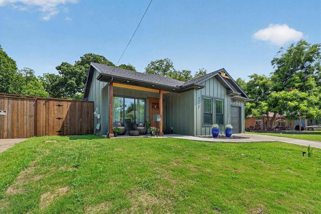 3210 Carpenter Avenue, Dallas, TX 75215 Board and batten siding, covered front porch with wood columns, attached garage, concrete driveway, and wood privacy fencing