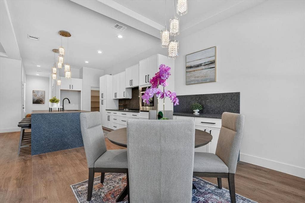 3210 Carpenter Avenue, Dallas, TX 75215 White cabinetry with dark hardware, recessed lighting, wood-finish flooring, dark textured kitchen island, and contemporary light fixtures