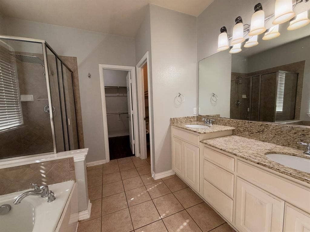 5016 Rushden Road, McKinney, TX 75070 Dual vanity with light-colored countertops, tile flooring, built-in bathtub, and a glass-enclosed shower