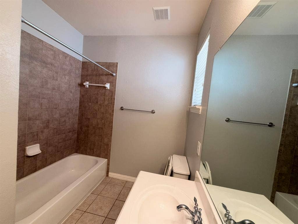 5016 Rushden Road, McKinney, TX 75070 Bathroom featuring a white bathtub, full wall tile surround, vanity with an integrated sink, and a large wall-mounted mirror