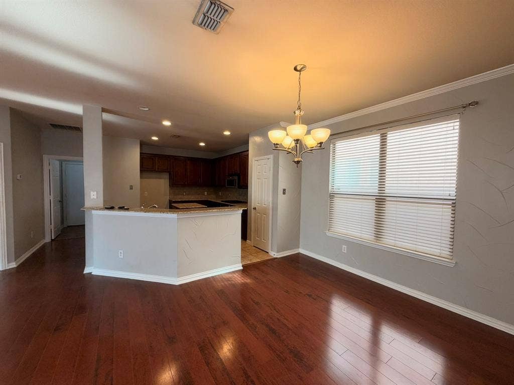 5016 Rushden Road, McKinney, TX 75070 Open-concept living area featuring rich wood-finish flooring and a kitchen with dark cabinetry