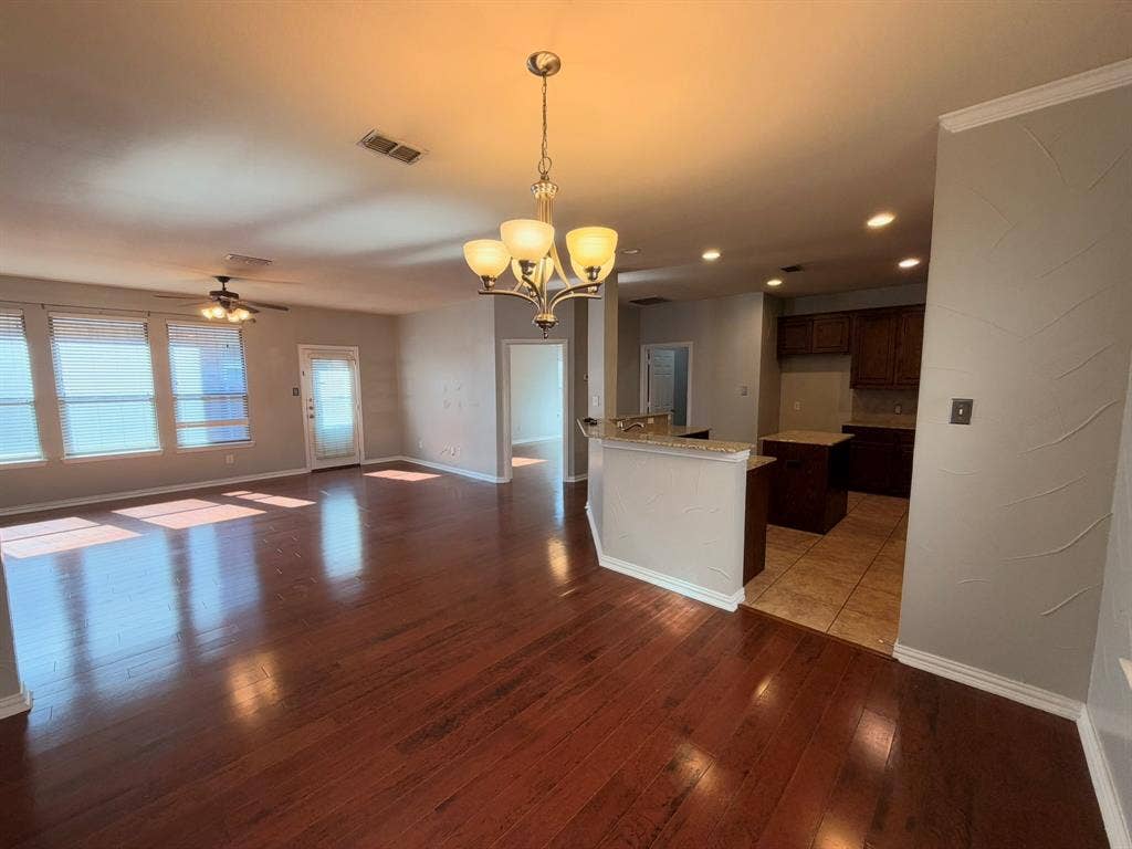 5016 Rushden Road, McKinney, TX 75070 Expansive living area with wood-finish flooring, multiple windows, and a ceiling fan