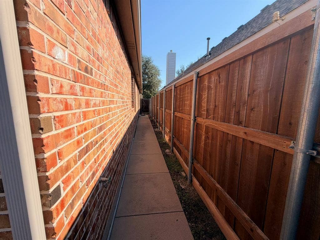 5016 Rushden Road, McKinney, TX 75070 Brick exterior with a concrete pathway and wood-panel fencing