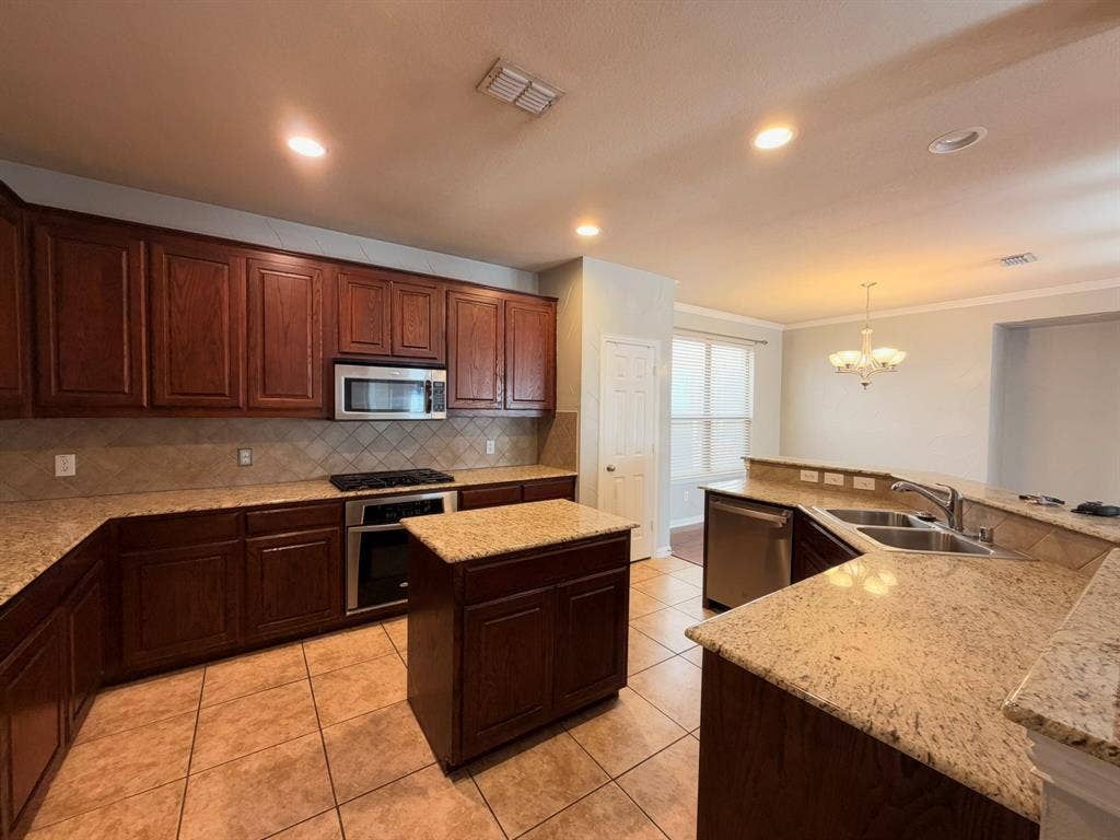 5016 Rushden Road, McKinney, TX 75070 Kitchen featuring wood cabinetry, granite countertops, tile flooring, and stainless steel appliances