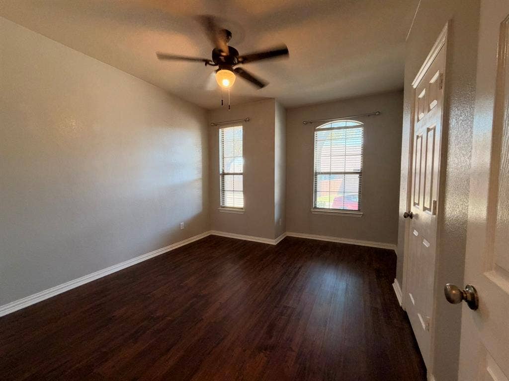 5016 Rushden Road, McKinney, TX 75070 Rich wood-finish flooring, two large windows with blinds, and a ceiling fan with integrated lighting