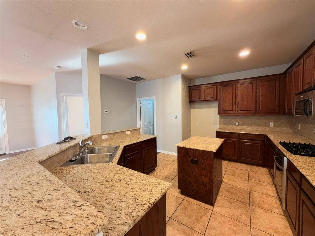 5016 Rushden Road, McKinney, TX 75070 Kitchen featuring recessed lighting, a central island, wood cabinetry, granite countertops, and tile flooring