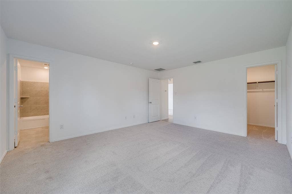 3700 Bluebird Lane, McKinney, TX 75071 Unfurnished bedroom with a closet, carpet floors, connected bathroom, and a walk in closet