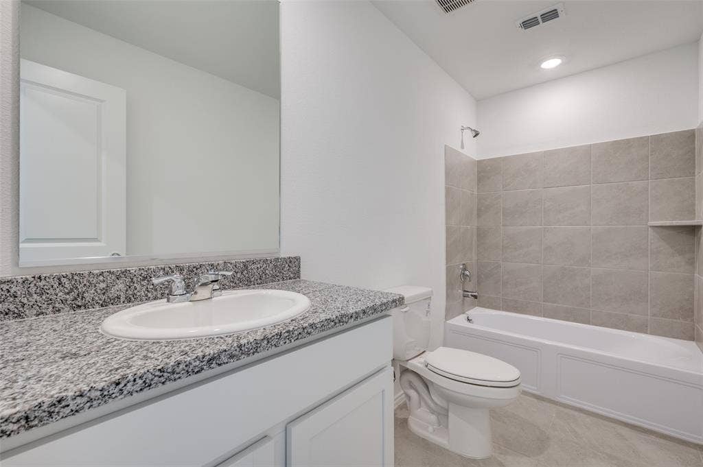 3700 Bluebird Lane, McKinney, TX 75071 Full bathroom with tile floors, tiled shower / bath combo, large vanity, and toilet