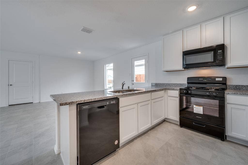 3700 Bluebird Lane, McKinney, TX 75071 Kitchen with white cabinetry, black appliances, light tile floors, and kitchen peninsula
