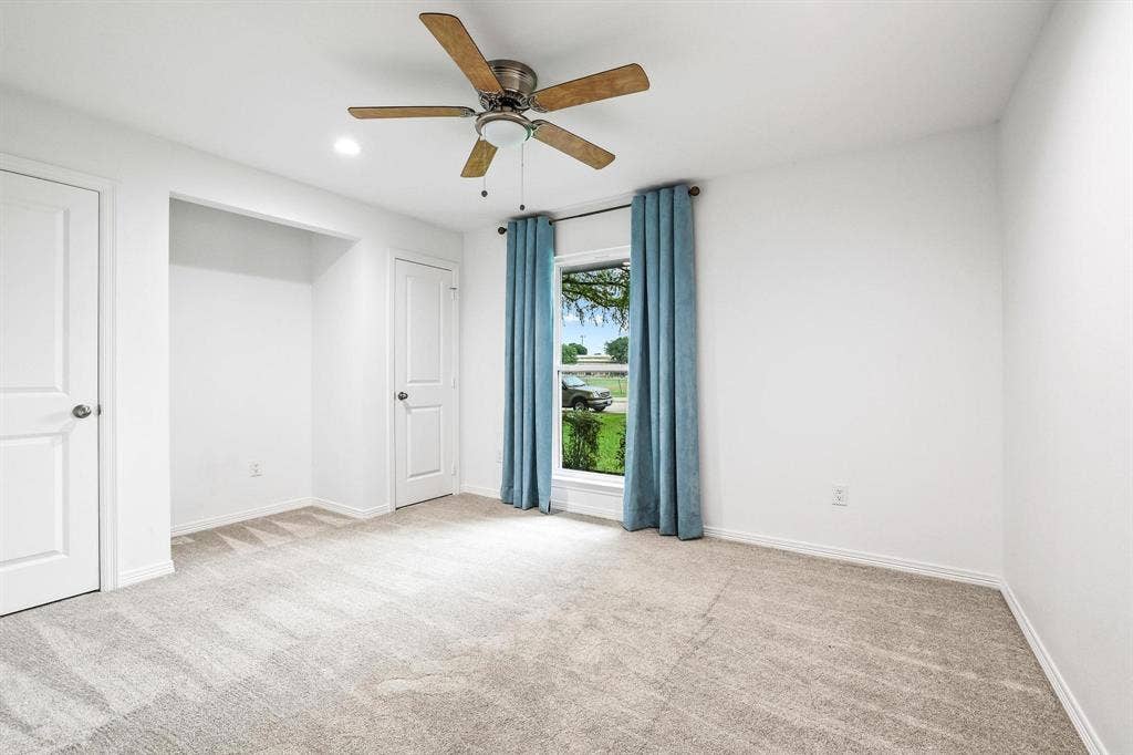 7668 La Cosa Drive, Dallas, TX 75248 Downstairs Bedroom 3, Neutral tone carpeting, white walls, ceiling fan with light, recessed lighting, and a window with a white frame