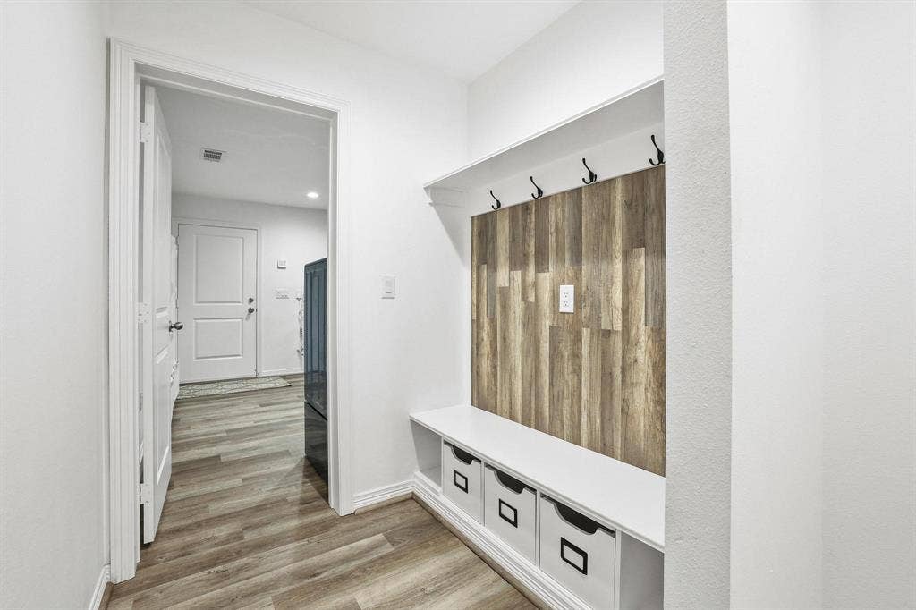 7668 La Cosa Drive, Dallas, TX 75248 Built-in mudroom bench with storage cubbies, wood-finish accent wall, and wall-mounted hooks