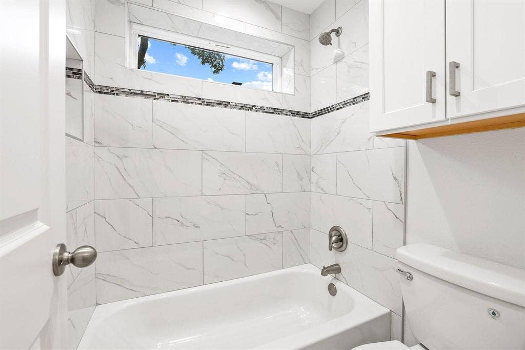 7668 La Cosa Drive, Dallas, TX 75248 Bathtub with white subway tile surround and decorative mosaic accent