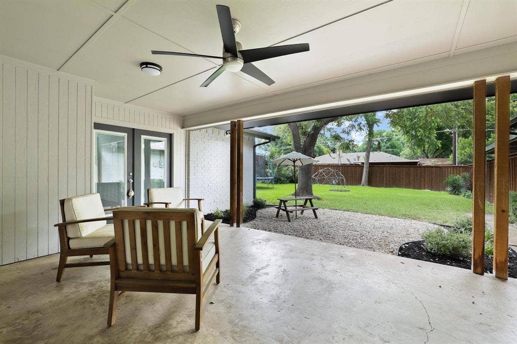7668 La Cosa Drive, Dallas, TX 75248 Covered patio with a ceiling fan, concrete flooring, and direct access to a spacious backyard featuring a gravel path and mature trees
