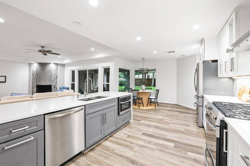 7668 La Cosa Drive, Dallas, TX 75248 Open-concept kitchen featuring light wood-finish flooring, white countertops, stainless steel appliances, and grey cabinetry