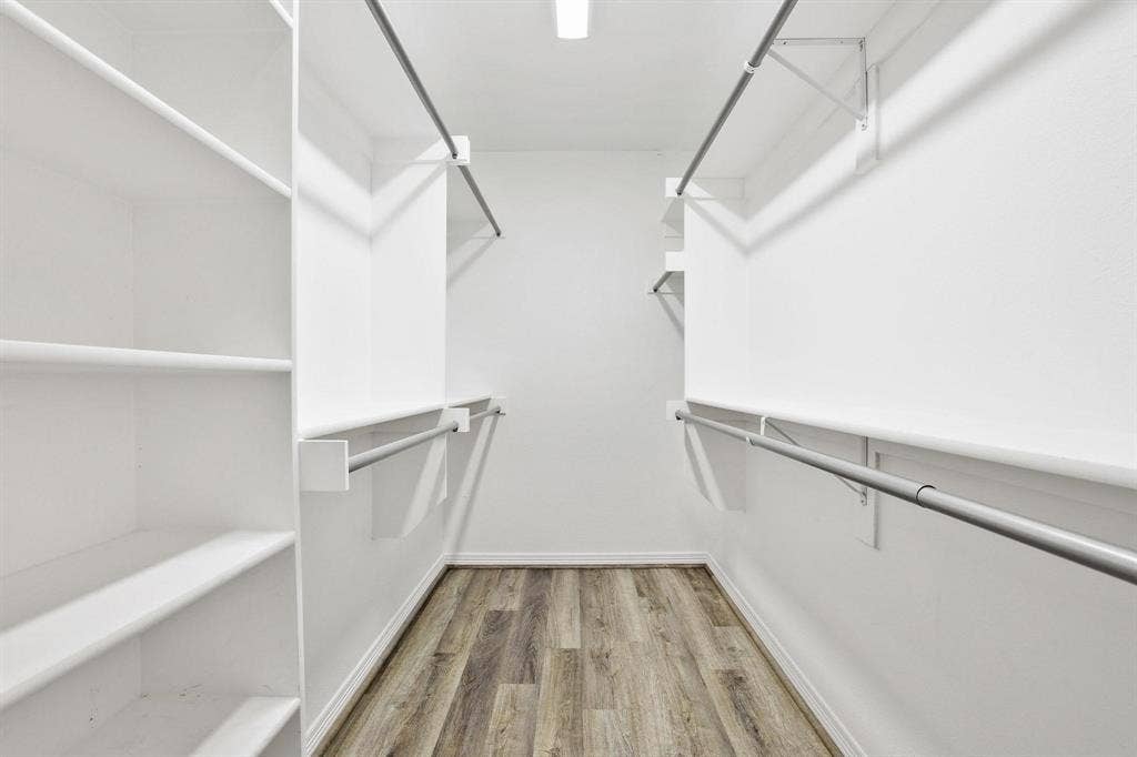 7668 La Cosa Drive, Dallas, TX 75248 Walk-in closet featuring wood-finish flooring, built-in shelving, and multiple clothing rods