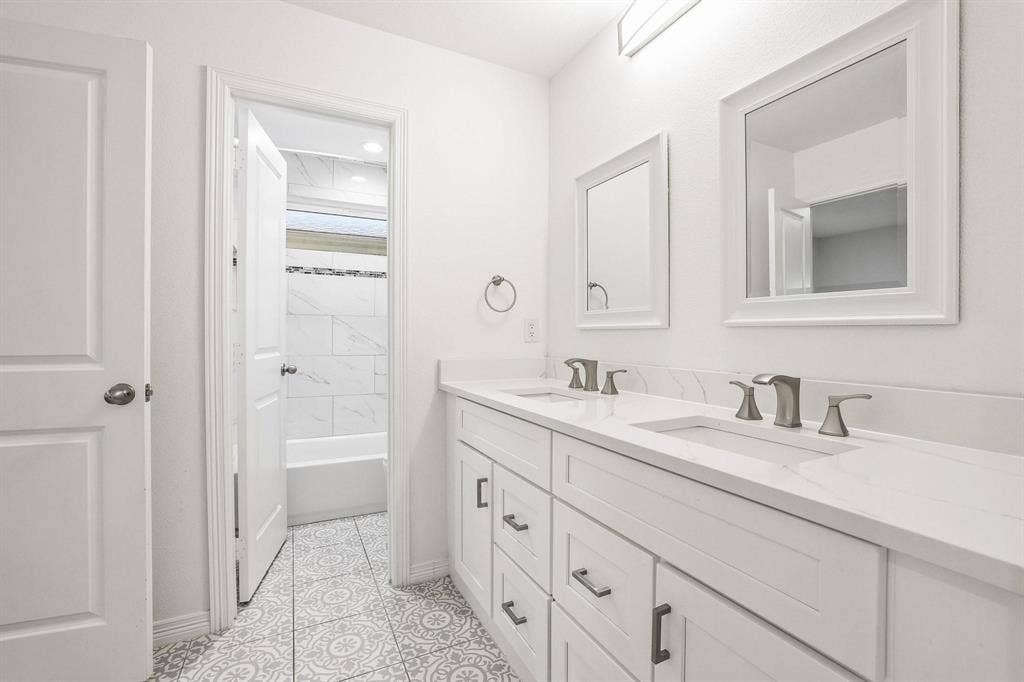 7668 La Cosa Drive, Dallas, TX 75248 Dual vanity with white shaker-style cabinetry, undermount sinks, and brushed nickel fixtures