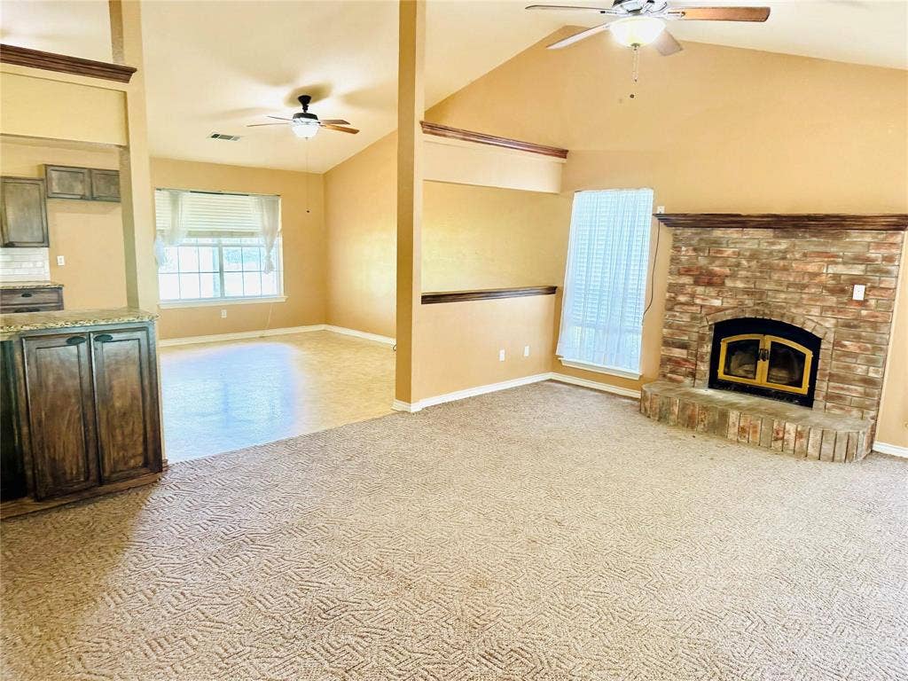 12875 Westover Lane, Anna, TX 75409 Living area featuring a stone-clad fireplace with hearth, vaulted ceiling, and ceiling fan
