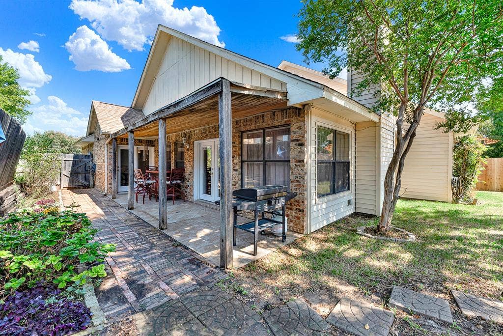 A rustic covered patio with brick paving transitions smoothly into the lush grassy yard. Imagine firing up the grill for casual weekend cookouts while guests relax in the shade.