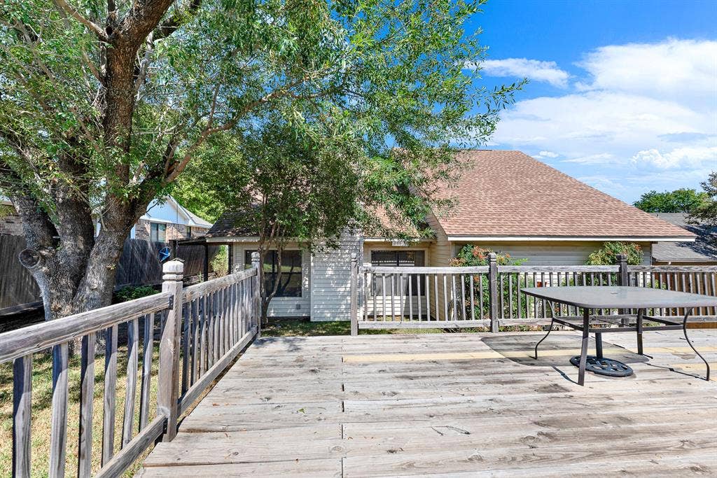 Railing-enclosed decking provides a dedicated outdoor dining platform framed by leafy branches. It offers an idyllic spot to share outdoor meals surrounded by soft backyard breezes.