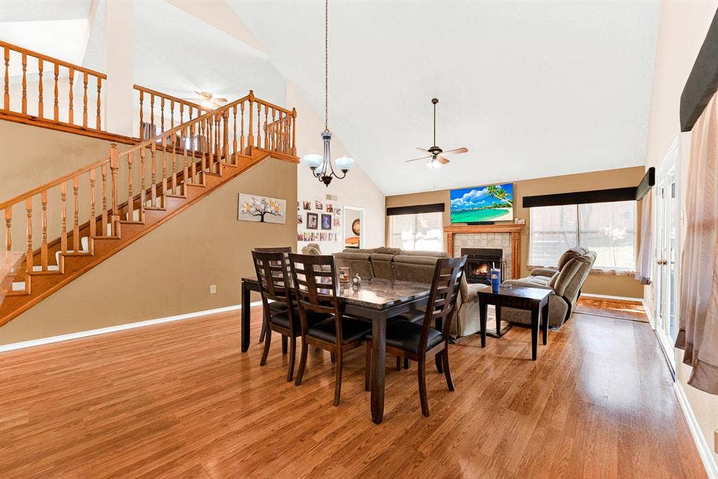 Warm wood-plank flooring spans seamlessly beneath the grand staircase, framing a airy layout that feels both spacious and connected. Imagine enjoying a festive holiday feast with family while soft firelight glows across the open main level.
