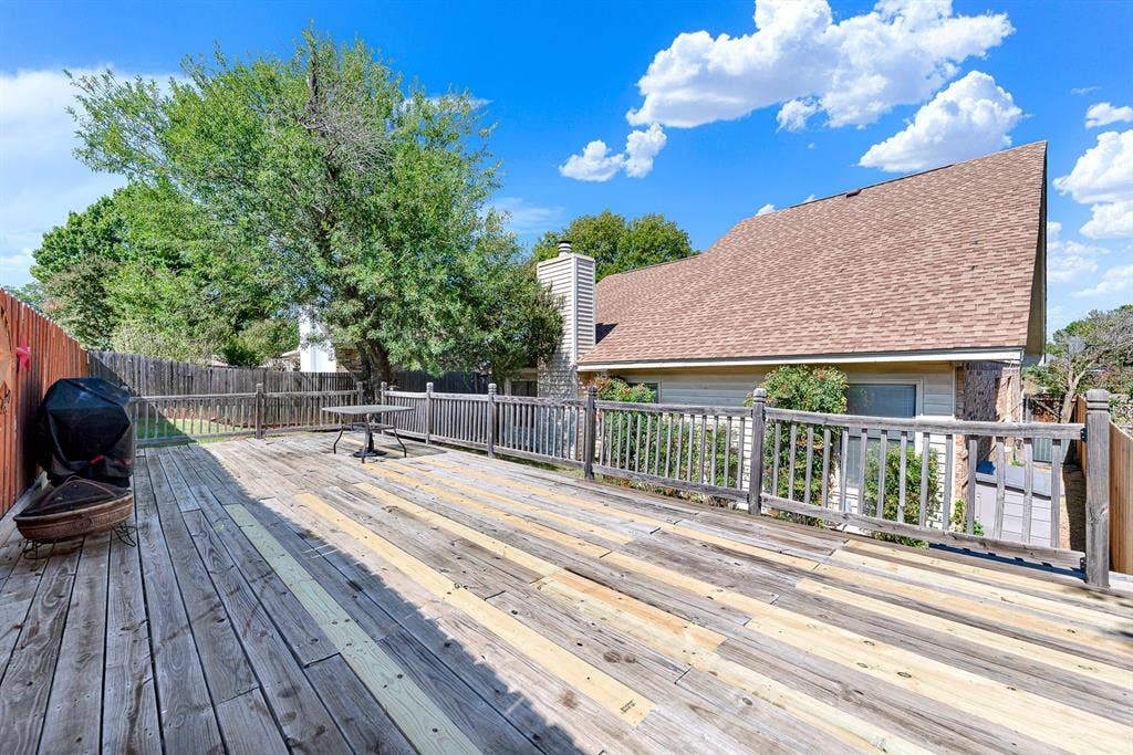 An expansive wooden deck provides an elevated vantage point surrounded by tree-canopied greenery. Picture setting up outdoor loungers for evening stargazing or hosting lively summer get-togethers.