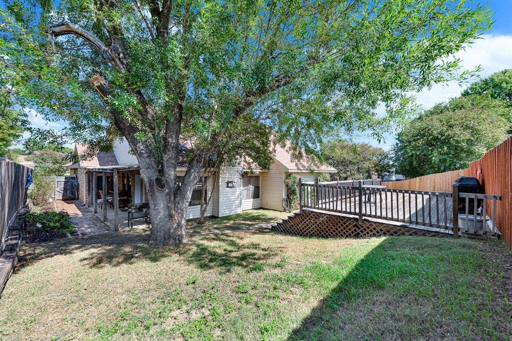 Broad tree branches cast cool, dappled shadows across the multi-level outdoor living space. You can easily envision hosting backyard barbecues that comfortably flow between the covered patio and open deck