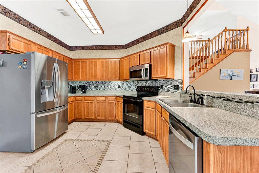 A wraparound layout with generous counter space, textured tile floors, and a glass tile backsplash keeps cooking effortless. Picture preparing weekend family breakfasts while easily chatting with guests at the pass-through bar.