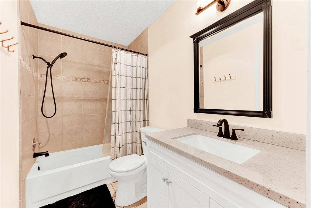 A crisp white vanity paired with oil-rubbed bronze fixtures and a tiled bath surround creates a clean, refreshed aesthetic. Visitors will appreciate having a dedicated, stylish space to prepare for the day in total comfort.