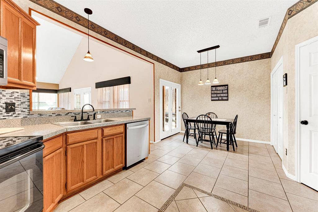 Expansive tile flooring connects the prep space to the dining alcove in one continuous, open layout. This seamless flow makes setting the table and serving fresh home-cooked meals feel completely effortless