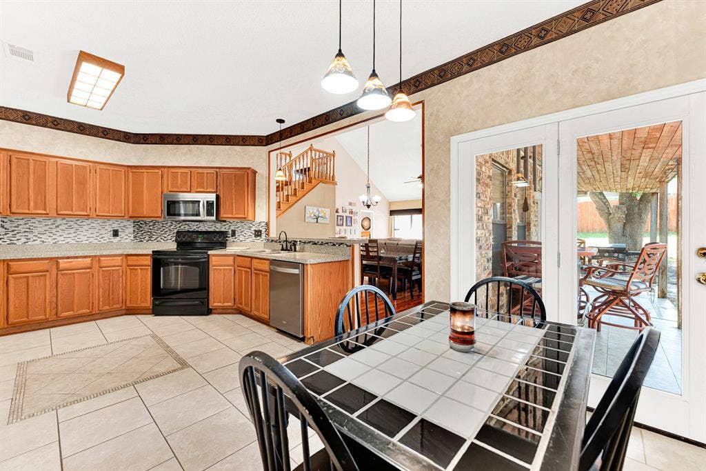 Pendant lighting highlights the transitions between the kitchen workspace, breakfast dining area, and covered back porch. It offers an inviting setting to enjoy relaxed evening dinners that naturally extend outside onto the patio.