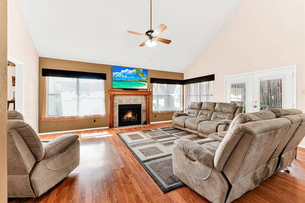 Expansive double-hung windows framed by soft window treatments draw gentle daytime sunlight across rich wood-toned flooring. It creates an idyllic setting for sipping your morning coffee while watching sunlight drift across the room.