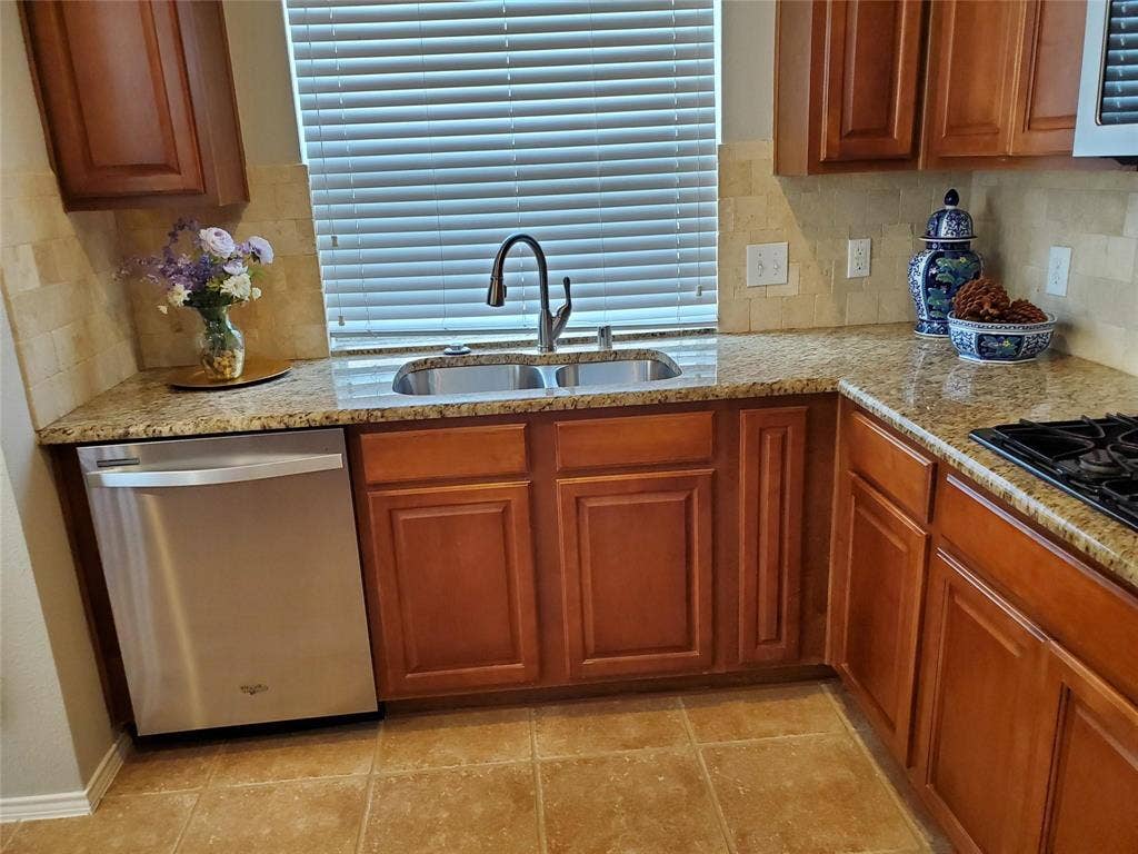 2077 Sleepy Hollow Trail, Frisco, TX 75033 Kitchen featuring light tile patterned flooring, dishwasher, backsplash, light stone counters, and sink