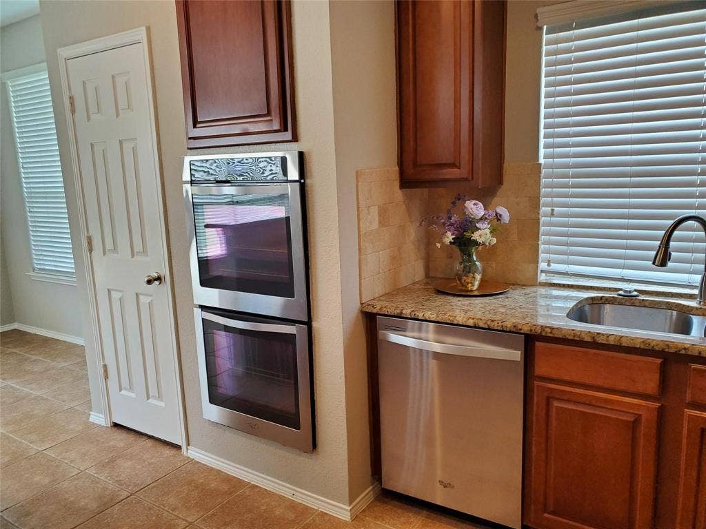 2077 Sleepy Hollow Trail, Frisco, TX 75033 Kitchen with light stone counters, appliances with stainless steel finishes, light tile patterned flooring, backsplash, and sink
