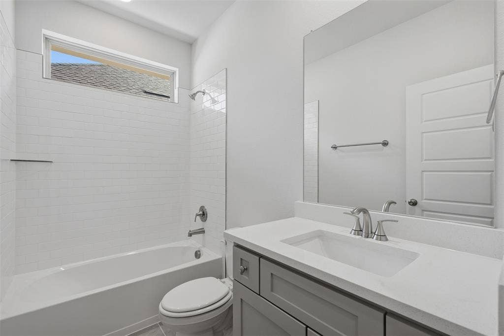 Bathtub with subway tile surround, sleek vanity with an integrated sink, and a large wall-mounted mirror
