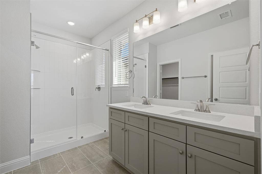 Double vanity with under-mount sinks, light-toned countertop, and grey cabinetry