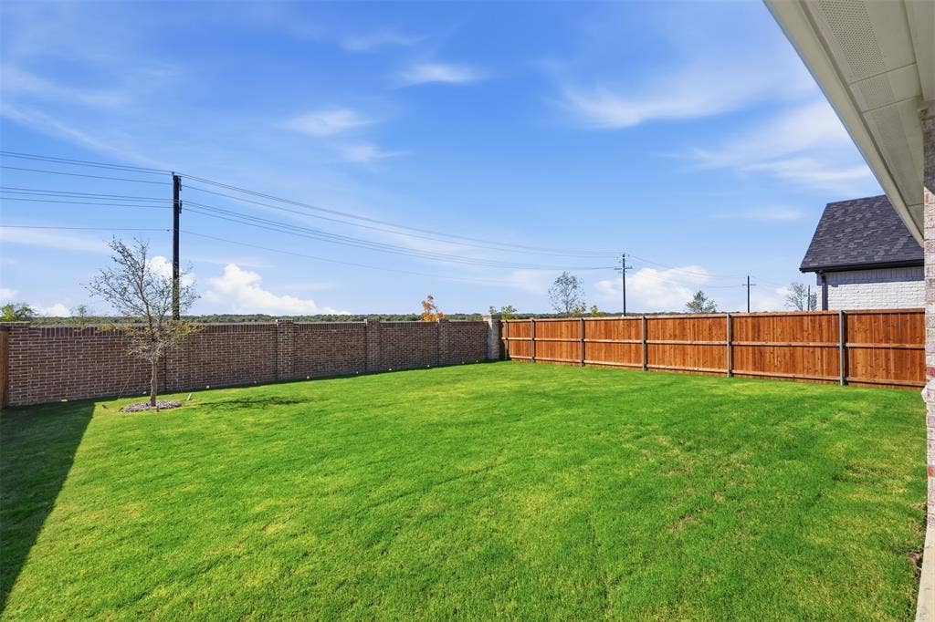 Expansive lawn with a wooden privacy fence and a brick perimeter wall