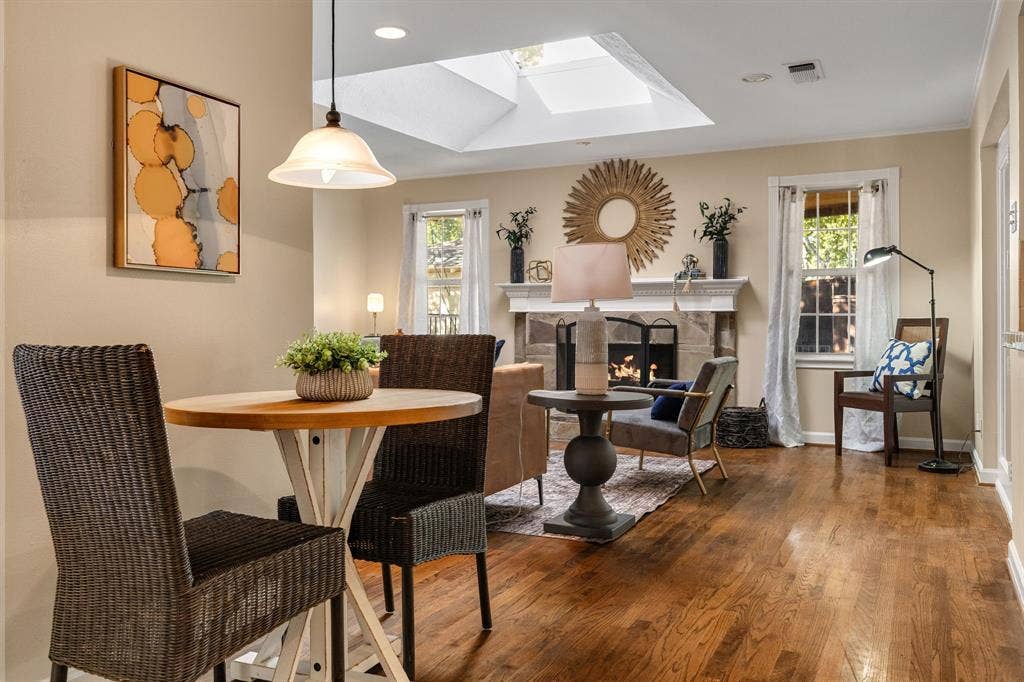 824 Westwood Drive, Richardson, TX 75080 Wood-finish flooring, stone-surround fireplace with a detailed mantel, skylight, and pendant lighting