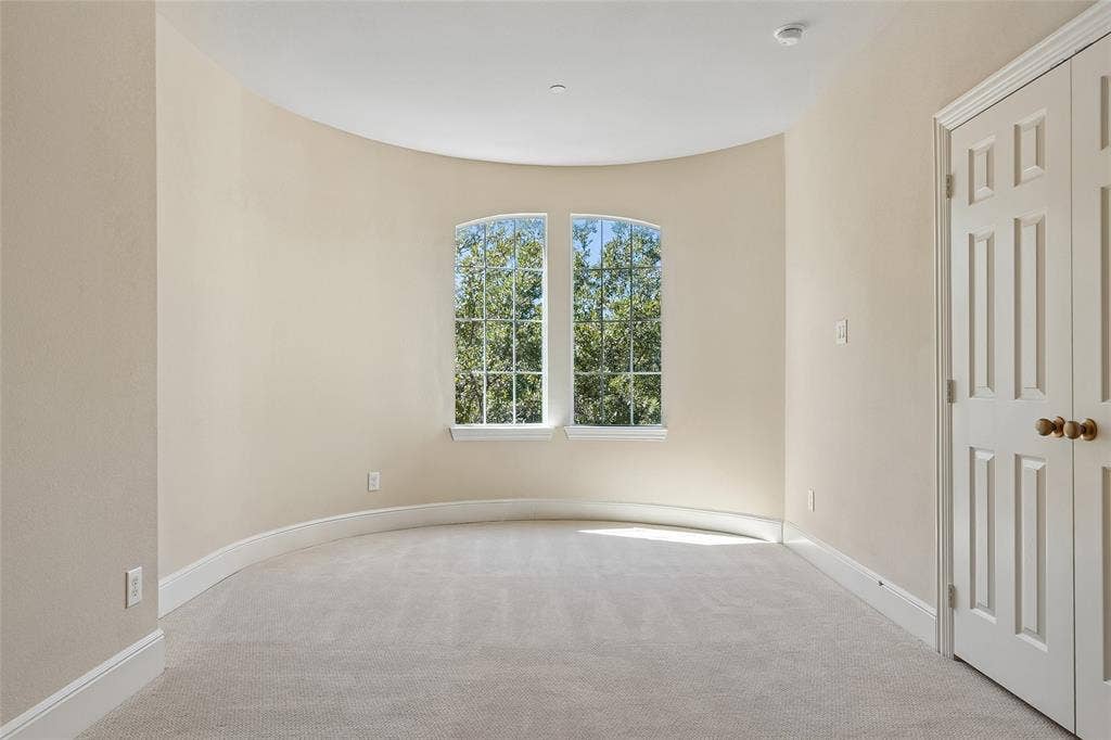 Curved wall architecture, arched window, soft neutral wall color, recessed ceiling lighting, and paneled doors